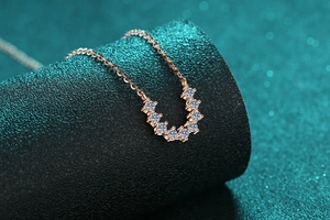 Vue macro du pendentif en forme de U en or rose avec sept pierres étincelantes sur chaîne