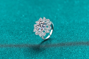 Macro shot of 925 silver ring with sunflower petal moissanite cluster on teal glitter background
