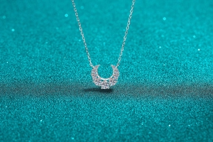 Macro shot of silver crescent pendant with sparkling stones on blue background