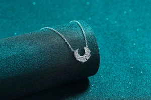 Macro detail of silver crescent necklace with five moissanite stones on a pedestal