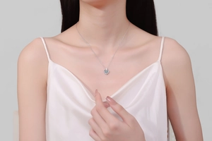 Close-up of a heart-shaped moissanite pendant necklace worn by a female model