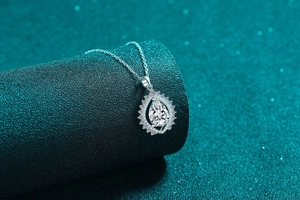 Detailed close-up of a pear-shaped moissanite pendant with halo setting on a silver chain