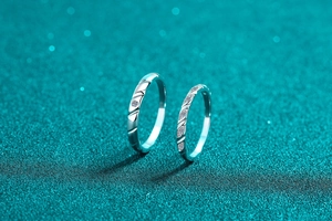 Dettaglio macro di anelli di coppia in argento S925 con moissanite su fondo glitter