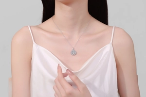 Close-up of S925 silver pear-shaped moissanite necklace worn by a model on white silk