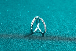 Macro di anelli di coppia in argento 925 con moissanite su uno sfondo verde acqua
