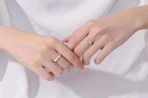 Close-up of S925 sterling silver minimalist couple rings worn on hands with soft shadows
