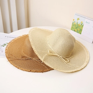 Women's wide brim straw sun hat with frayed edges and bow for beach sun protection
