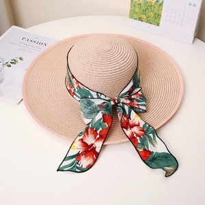 Detail of wide brim straw hat featuring floral ribbon bow and tight weave texture