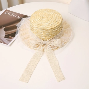 Close-up of flat straw boater hat featuring lace bow ribbon and elegant mesh brim detail