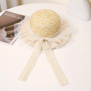 Close-up of a straw sun hat featuring delicate lace trim and a dotted mesh ribbon tie