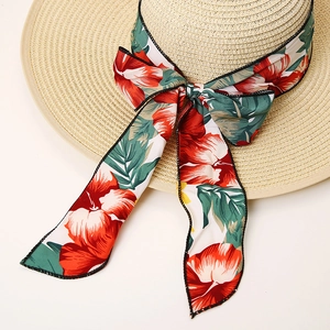 Close-up of woven straw hat featuring a tropical floral print ribbon with a bow knot
