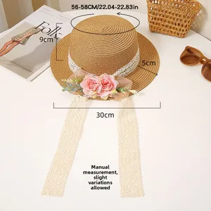 Detail of summer straw hat with white lace trim, pink flowers, and decorative ribbons