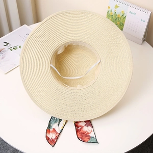 Detail of beige straw sun hat featuring floral ribbon trim and adjustable windproof strap