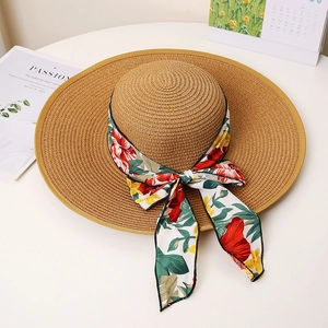 Close-up of wide brim straw hat featuring vibrant floral ribbon and elegant bow detail