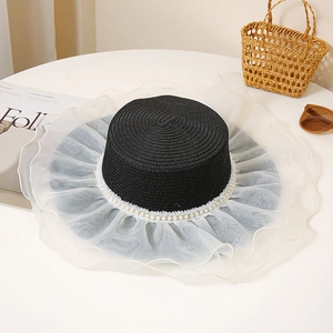 Close-up of black straw hat featuring white organza brim and elegant pearl trimming
