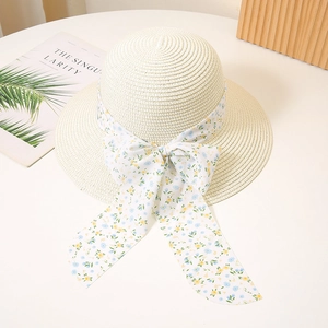 Detail of cream straw sun hat with floral ribbon bow and textured woven pattern