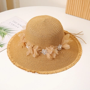 Detail eines Strohhuts mit breiter Krempe, Organza-Blüten und Perlenverzierung