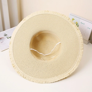 Detail of beige straw sun hat showing frayed edges and adjustable white windproof strap