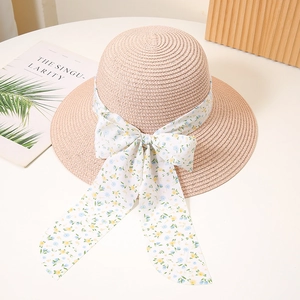 Close-up of pink woven sun hat featuring a wide floral ribbon and elegant bow detail