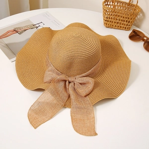 Close-up of wide-brim straw hat with soft mesh bow tie and wavy edges on white background