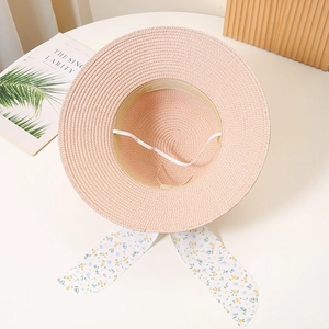 Close-up of pink straw hat interior featuring sweatband, chin strap and floral ribbon