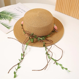 Détail du chapeau en paille tissé à la main avec décoration florale et feuilles vertes