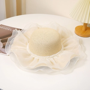 Détail d'un chapeau de paille avec bord en organza à volants et décor de perles