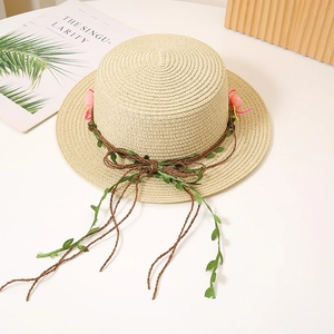 Détail d'un chapeau de paille beige à bord plat avec décor floral et accents de fleurs roses