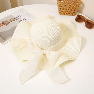 Detailed close-up of cream-colored straw sun hat with large bow and elegant woven texture