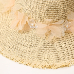 Detailaufnahme vom Strohhut mit Chiffon-Blumenakzenten und Perlenverzierungen