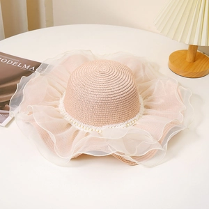 Détail d'un chapeau de paille à large bord avec dentelle organza et perles blanches