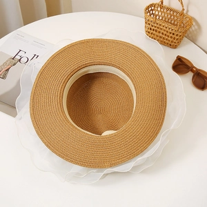 Detailed view of woven straw sun hat with elegant white lace trim and wavy organza edge
