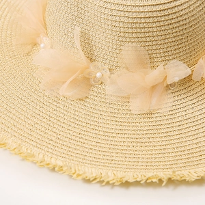 Detail of lace flowers, pearls, and straw weaving on wide brim summer sun hat