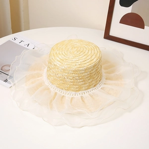 Détail du chapeau de paille avec bord en organza blanc et décoration de perles
