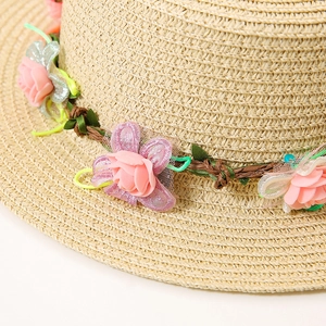 Gros plan sur les détails de la couronne de fleurs roses sur un chapeau de paille plat