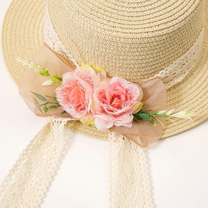 Detailed macro view of straw hat with white lace, pink roses, and organza bow accents