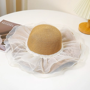 Détail d'un chapeau de paille élégant avec perles et bord ondulé en organza