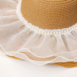 Détail d'un chapeau de paille avec bordure élégante en résille blanche et perles fantaisie