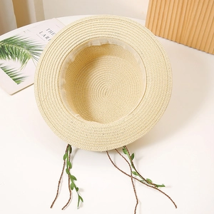 Détail d'un chapeau de paille avec cordons décoratifs en feuilles et texture rustique