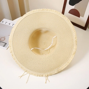 Detailed view of handmade straw hat with fringed edges and white elastic chin strap