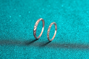Macro detail of rose gold moissanite rings featuring elegant wavy textures and diamond accents