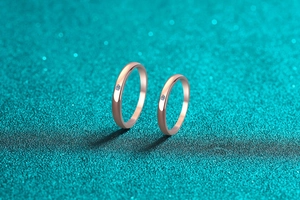 Detail of rose gold couples rings with central round diamond and polished finish
