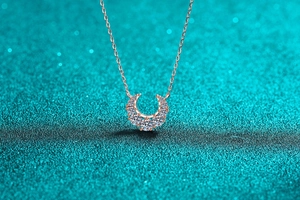 Vue macro d'un collier pendentif fer à cheval en or rose avec sept pierres brillantes