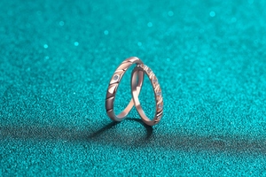Close-up of rose gold plated moissanite couple rings with diagonal wave texture