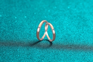 Close-up of rose gold couple rings with round brilliant diamonds on a shimmering backdrop