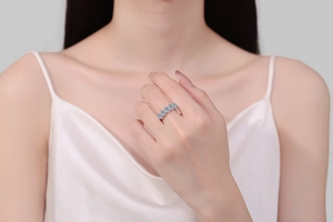 Close-up of a sterling silver ring with five oval-cut sky blue gemstones on a hand