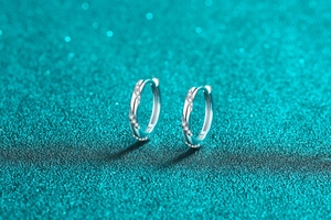 Close-up of S925 silver hoop earrings with spiral moissanite stones on blue texture
