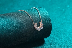 Détail d'un pendentif fer à cheval en or rose serti de pierres sur support vert
