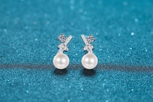 Macro shot of silver ribbon bow earrings with micro-pave crystals and round pearls