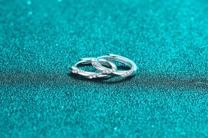 Macro shot of silver twisted rope earrings with micro-inlaid diamonds on blue background